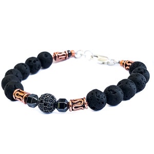 May include: Black lava rock beaded bracelet with copper and silver accents. The bracelet features a black gemstone bead in the center.