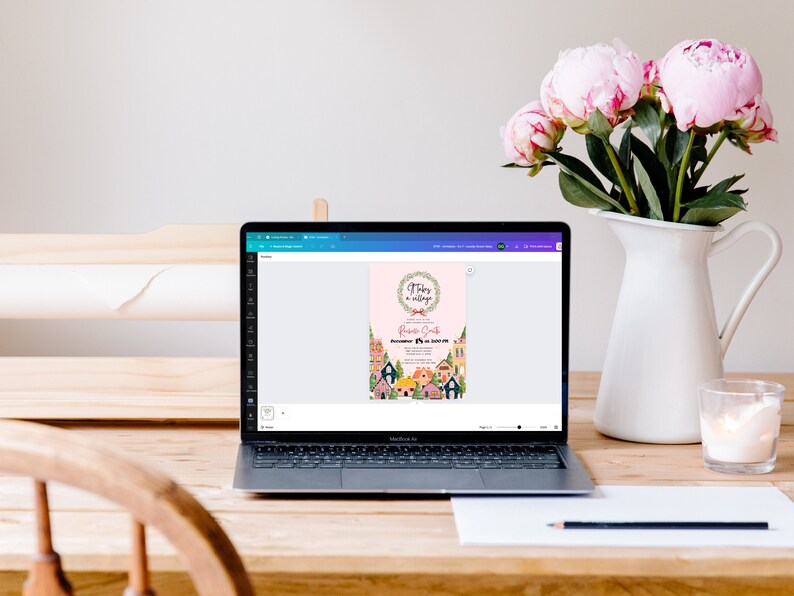 K&ouml;nnte beinhalten: Ein Laptop-Computer, auf dem eine digitale Einladung mit rosa Hintergrund und einem Blumenkranz angezeigt wird. Der Einladungstext lautet "There's a village in my belly" und "Baby Shower for Rosie Smith".