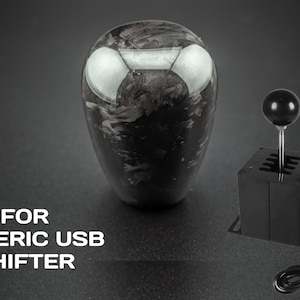 Può includere: Un pomello del cambio in fibra di carbonio nero con una sfera nera in cima e una base del cambio USB nera con un cavo.  FOR GENERIC USB SHIFTER.