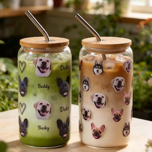 May include: Two glass tumblers with bamboo lids and metal straws. One contains a green beverage, the other a light brown drink. Both are decorated with dog face stickers and the names "Buddy", "Duke", and "Bucky".