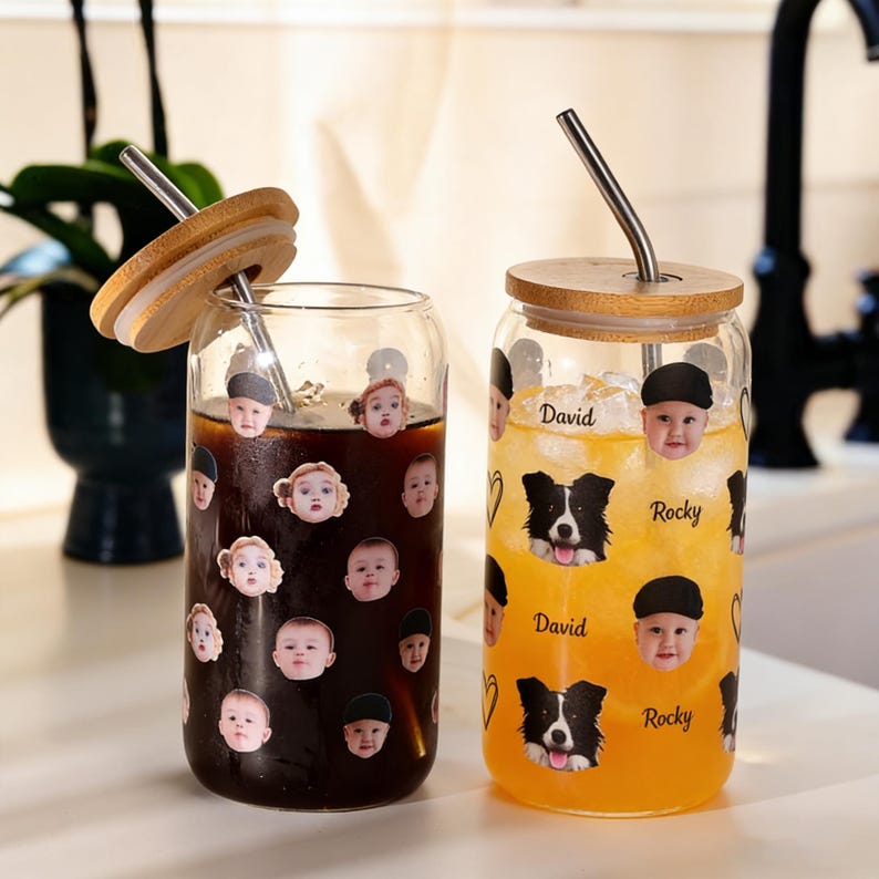 Puede incluir: Dos vasos de vidrio para beber con tapas de bamb&uacute; y pajitas de acero inoxidable. Una taza contiene un l&iacute;quido oscuro y est&aacute; decorada con caras de beb&eacute;. La otra taza tiene un l&iacute;quido naranja claro y presenta un gr&aacute;fico de perro y los nombres "David" y "Rocky."