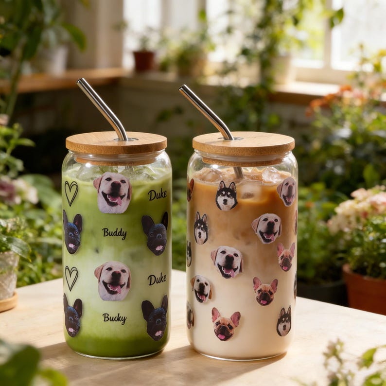 Puede incluir: Dos vasos de vidrio con tapas de bamb&uacute; y pajitas de metal. Uno contiene una bebida verde, el otro una bebida marr&oacute;n claro. Ambos est&aacute;n decorados con pegatinas de caras de perro y los nombres "Buddy", "Duke" y "Bucky".