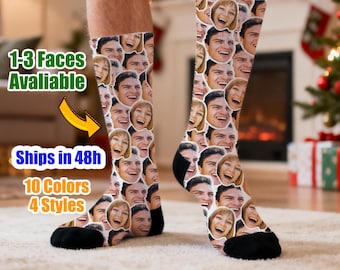 May include: A pair of socks featuring a collage of smiling faces. The socks have a black heel and toe, with the rest of the sock covered in various faces. The text "1-3 Faces Available" is visible in the image.