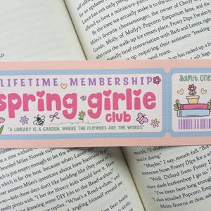 以下が含まれることがあります： ピンクとブルーのチケットデザインのブックマーク。 「Lifetime Membership Spring Girlie Club」と「図書館は花が言葉である庭である」と書かれています。