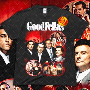 May include: Black t-shirt featuring a graphic design with the text "GoodFellas" in white, along with images of actors from the movie. The design includes a red background and several circular images. A "Free Shipping" sticker is visible.