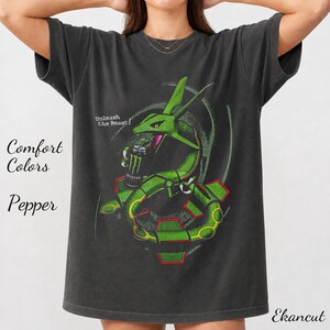 May include: A charcoal gray short-sleeve t-shirt featuring a graphic of a green serpentine creature holding a black energy drink can. The text "Unleash the Beast!" is printed above the creature. The shirt also displays the text "Comfort Colors Pepper" and "Ekancut" on the sides.