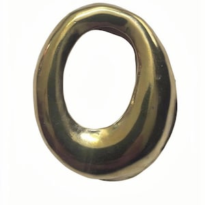 May include: A golden-colored, oval-shaped object with a smooth, reflective surface. The object has a hollow center and appears to be made of metal. The shape is slightly irregular, with rounded edges. The lighting creates highlights and shadows.