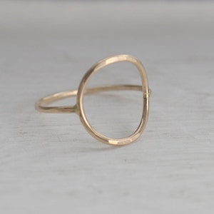 Puede incluir: Un anillo de oro simple con un diseño circular martillado. El anillo está hecho de una sola pieza de metal, con el círculo formando la banda.