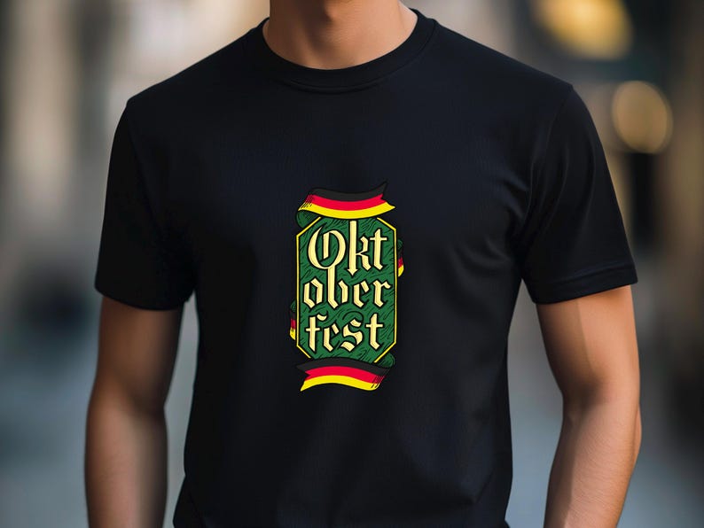 May include: Black t-shirt with a colorful Oktoberfest design. The graphic features the words "Oktoberfest" in a decorative font, framed by a green and yellow border with red and black accents. The shirt is made of a soft material.