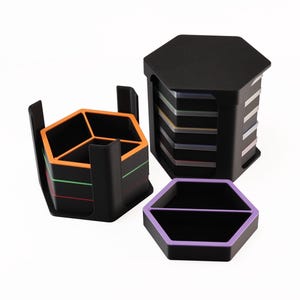 May include: Black hexagonal desk organizers with colorful accents. The set includes a stackable holder, a divided tray with a purple rim, and a multi-compartment organizer with orange and green stripes. Ideal for office or home organization.