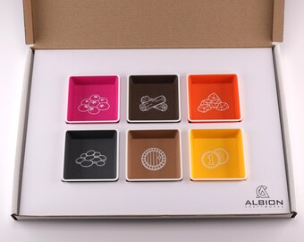 以下が含まれることがあります： 段ボール箱に入った、6つのカラフルな正方形のゲームコンポーネントトレイのセット。各トレイは異なる色で、ベリー、丸太、コインなどのゲームリソースを表す白いアイコンが含まれています。Albion Craftworksのロゴが右下にあります。