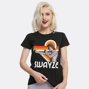 May include: Black t-shirt with a retro-style graphic of Patrick Swayze in a karate pose. The graphic features orange, red, and yellow stripes and the text "SWAYZE".