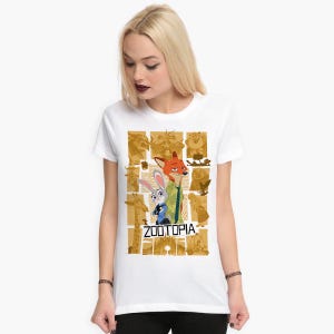 May include: White t-shirt with a graphic print of Judy Hopps and Nick Wilde from the movie Zootopia. The graphic is a collage of images from the movie in a gold and brown color scheme. The text "Zootopia" is printed in gold letters below the characters.