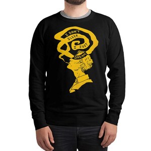 May include: Black sweatshirt with a yellow illustration of a person with a thought bubble above their head. The thought bubble reads "I don't sleep... I just dream". The person is smoking a cigarette.