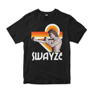 May include: Black t-shirt with a retro graphic of a man in a karate pose. The graphic is in orange, yellow, and red with the text "SWAYZE" in white.