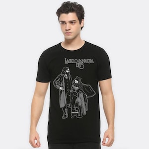 May include: Black t-shirt with a white graphic print of two figures, a man and a woman, with the text "Laszlo & Nadja Hits" above them.
