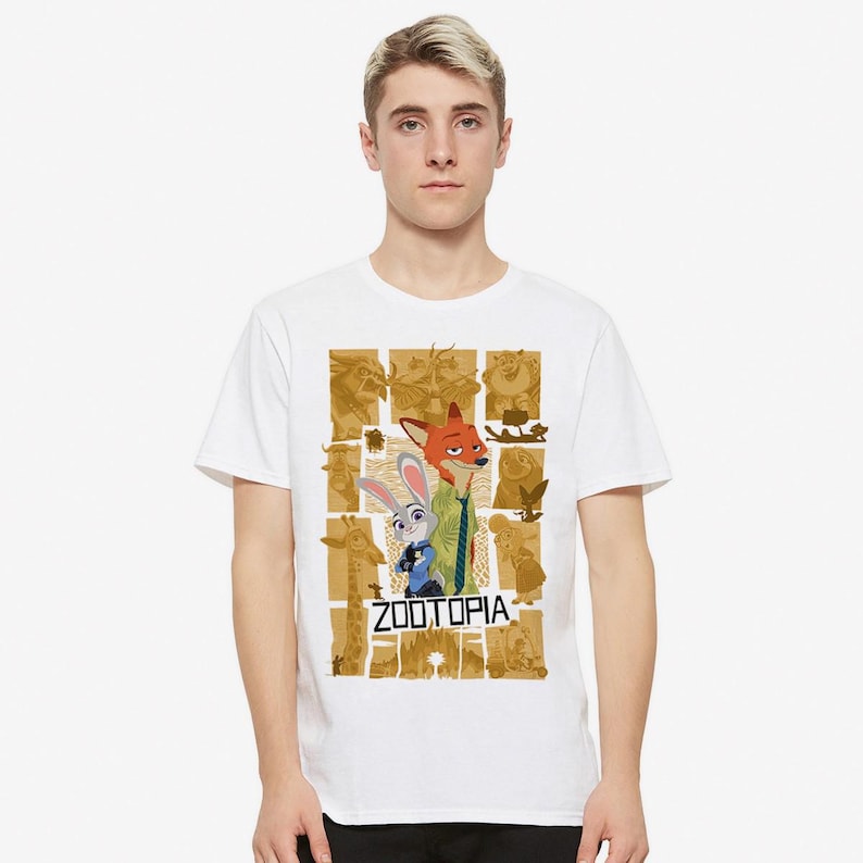 May include: White t-shirt with a graphic print of the characters Judy Hopps and Nick Wilde from the movie Zootopia. The graphic is a collage of images from the movie, including a giraffe, a sloth, and a fox. The text "Zootopia" is printed in black letters below the characters.