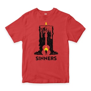 Puede incluir: Camiseta roja con un gráfico negro de una vela con una silueta de guitarra, una figura y la palabra "SINNERS" en blanco. La vela tiene una llama amarilla y cera goteando.