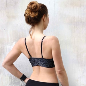 May include: A black sports bra with a geometric pattern. The bra has thin straps and a racerback design.