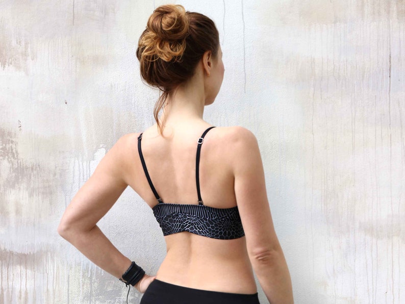 May include: A black sports bra with a geometric pattern. The bra has thin straps and a racerback design.