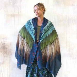 Puede incluir: Un chal azul oscuro con un gran dise&ntilde;o de alas en tonos verdes, azules y marrones. Las alas est&aacute;n extendidas, creando un efecto dram&aacute;tico. El chal tiene un estampado floral y detalles rojos.