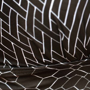 May include: Black fabric with a white geometric pattern. The fabric has a woven texture and a subtle sheen.