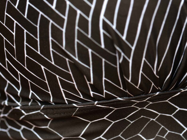 May include: Black fabric with a white geometric pattern. The fabric has a woven texture and a subtle sheen.