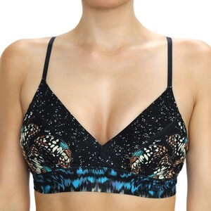 May include: A black bralette with a butterfly print. The bralette features a V-neck design with thin black straps. The top portion has a speckled pattern, while the lower section showcases a blue and black design.