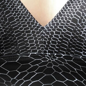 May include: Black and white patterned fabric with a geometric design. The fabric has a smooth, silky texture.