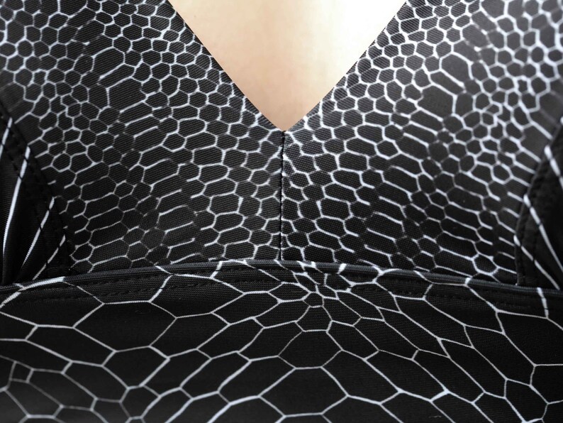 May include: Black and white patterned fabric with a geometric design. The fabric has a smooth, silky texture.