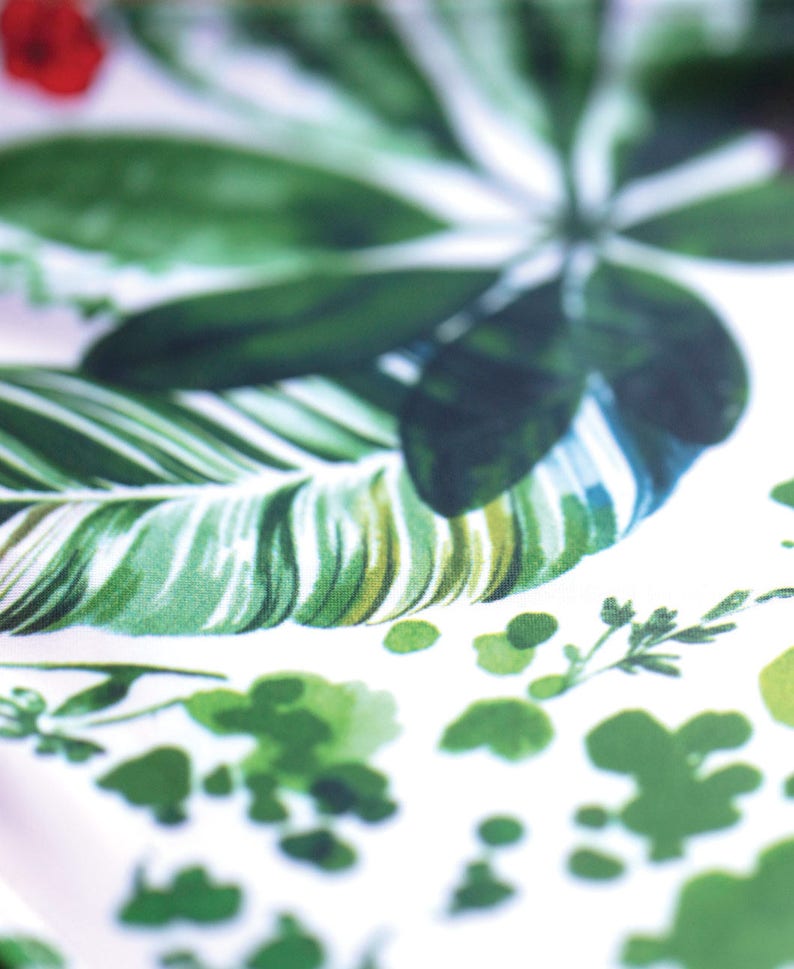 May include: White fabric with a green tropical leaf pattern. The leaves are in various shades of green and have a watercolor effect.