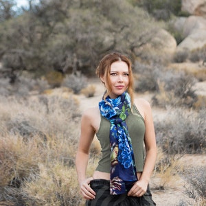 Peut inclure: Une femme portant un d&eacute;bardeur vert et une &eacute;charpe &agrave; motifs floraux bleus et verts. Elle se tient dans un paysage d&eacute;sertique.