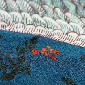 Puede incluir: Primer plano de un textil color turquesa con un dise&ntilde;o floral. La tela presenta ramas de color verde oscuro y peque&ntilde;as flores naranjas. La parte superior de la imagen muestra un patr&oacute;n blanco y azul claro, posiblemente un dise&ntilde;o de olas o plumas.