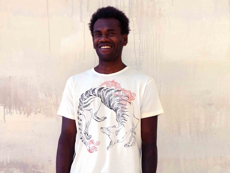May include: A white t-shirt featuring a black and white graphic of a stylised animal with red floral accents. The animal is curled into a circle.
