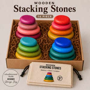 May include: A 16-piece set of wooden stacking stones in a cardboard box, featuring four stacks of smooth, colorful, rounded wooden discs in shades of red, pink, blue, green, and yellow, accompanied by a beige drawstring storage bag with text.
