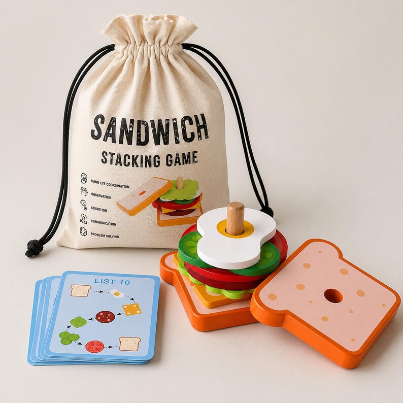 Pu&ograve; includere: Un gioco di impilamento sandwich in legno con un sacchetto beige con coulisse stampato con SANDWICH STACKING GAME, una pila di pezzi di cibo in legno colorati tra cui pane, lattuga, pomodoro e uovo, e un mazzo di carte blu etichettate LIST 10.