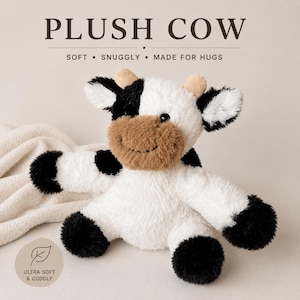 May include: A plush cow toy featuring white fur with black patches on the ears, arms, and legs, and a brown muzzle. The toy has small tan horns and black eyes. Text above reads PLUSH COW, SOFT, SNUGGLY, MADE FOR HUGS. A circular badge reads ULTRA SOFT & CUDDLY.