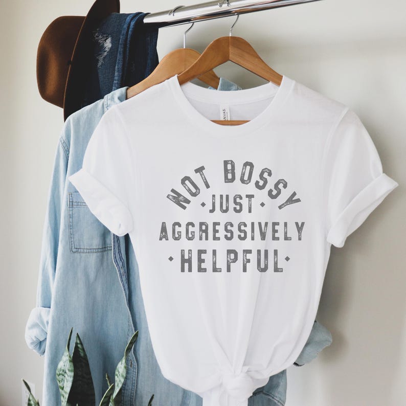 Puede incluir: Camiseta blanca con un gr&aacute;fico gris que dice "Not Bossy, Just Aggressively Helpful".