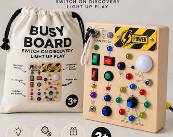 May include: A light-colored wooden busy board featuring various switches, buttons, and eleven LED lights, accompanied by a canvas drawstring storage bag. The board includes a yellow and black power label, a ferris wheel design, and a main switch with keys.