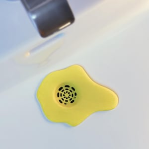 Può includere: Un set di tre tazze in ceramica con finitura opaca e macchiettata. Ogni tazza presenta un colore diverso: azzurro, crema e grigio. Le tazze hanno un design semplice e moderno con una forma arrotondata e un manico confortevole.
