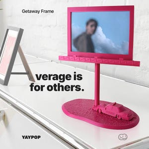 May include: A fuchsia-colored photo frame with a stand, featuring a picture of a person against a cloudy sky. The frame has a billboard-like design with a small police car at the base. Text on the frame reads "verge is for others."