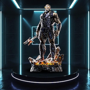Puede incluir: Estatua detallada de una figura humanoide musculosa con una expresión severa, sosteniendo un arma. La figura está vestida con una armadura oscura y se encuentra sobre una base rocosa con acentos de fuego. La estatua se exhibe en una plataforma negra.