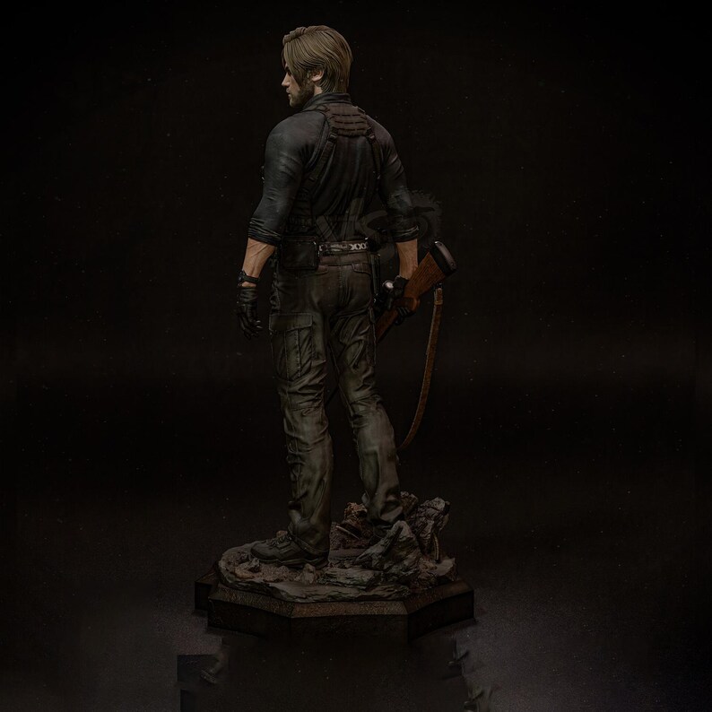 May include: A detailed figurine of a character from a video game, viewed from the back. The figure is dressed in a black shirt, dark pants, and gloves, holding a rifle. The base is a rocky terrain, and the overall color scheme is dark and realistic.