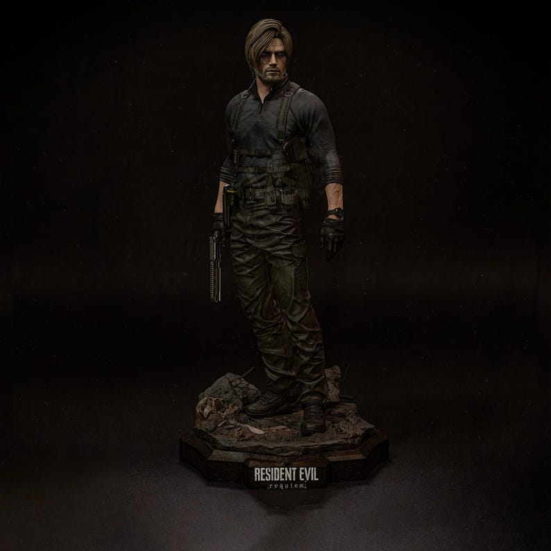 May include: A detailed figurine of a character from Resident Evil, dressed in a black tactical outfit and holding a gun. The figure stands on a rocky base with the text "RESIDENT EVIL requiem" at the bottom. The figure has short brown hair and is wearing black gloves.