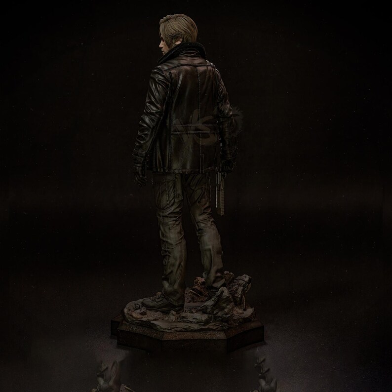 May include: A detailed statue of a character from a video game, viewed from the back. The figure wears a black leather jacket, dark pants, and gloves, holding a gun. The statue is on a rocky base, with a dark background.