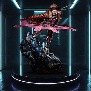 May include: A detailed statue of the Marvel Comics character Gambit in a dynamic pose, wielding a staff and energy. The figure is atop a blue and gray robotic hand, with pink energy effects. The statue is displayed on a black circular platform.