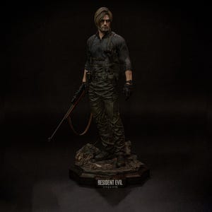 May include: A detailed figurine of a man in tactical gear, holding a rifle. The figure is dressed in a dark outfit with gloves and a utility belt. The base of the figurine reads "RESIDENT EVIL requiem."