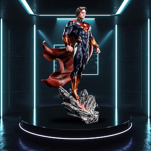 Op de afbeelding: Gedetailleerd beeld van een superheld in een dynamische pose, gekleed in een blauw en rood pak met een wapperende rode cape. Het beeld staat op een rotsachtige basis bovenop een zwart voetstuk, tegen een futuristische neonachtergrond.