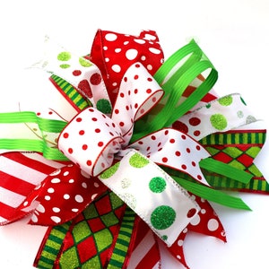 Pu&ograve; includere: Un fiocco natalizio festivo realizzato con nastro rosso, bianco e verde. Il fiocco presenta pois, strisce e un motivo a scacchi.