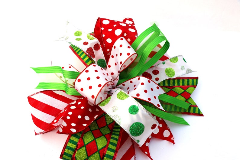 Pu&ograve; includere: Un fiocco natalizio festivo realizzato con nastro rosso, bianco e verde. Il fiocco presenta pois, strisce e un motivo a scacchi.